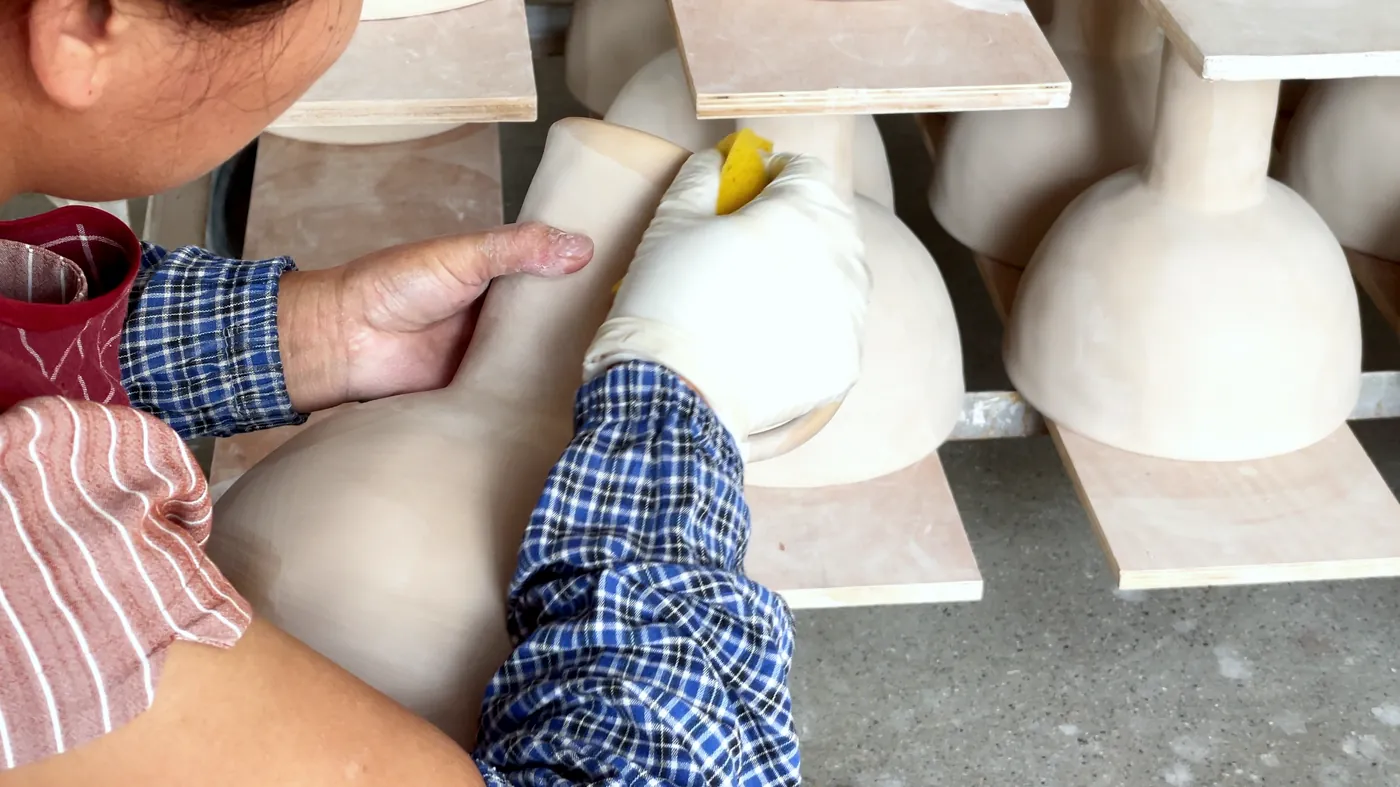 Hands sponging a leather-hard piece