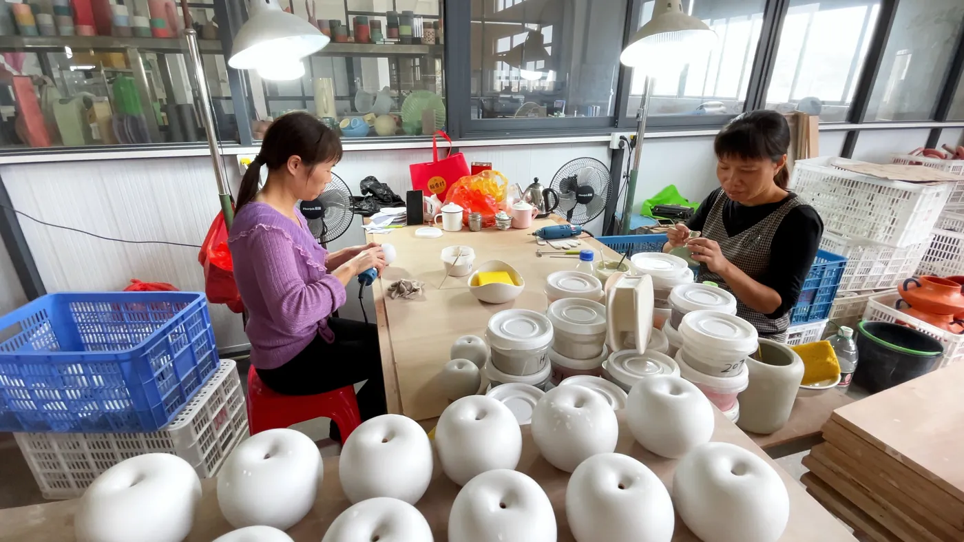 Checking white vases at the packing table